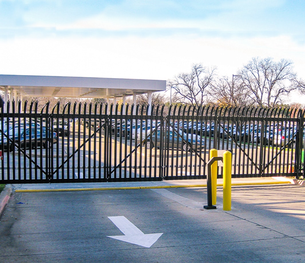 Commercial-grade metal fence installed at the entrance and exit of a parking lot